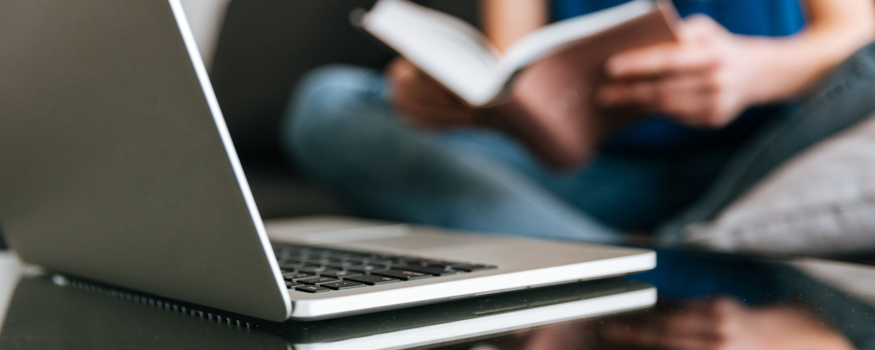 laptop-table-near-woman-reading-book-home